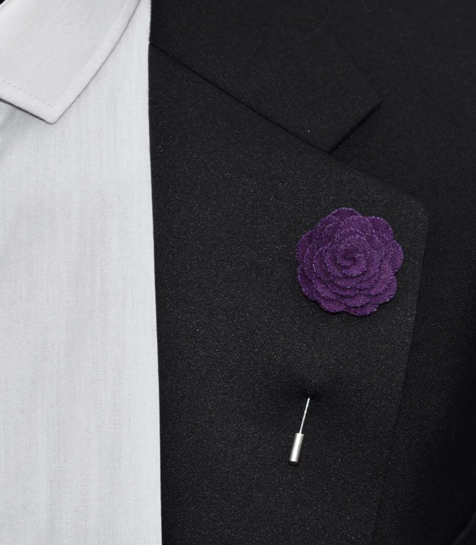 Purple floral lapel pin on a black suit jacket