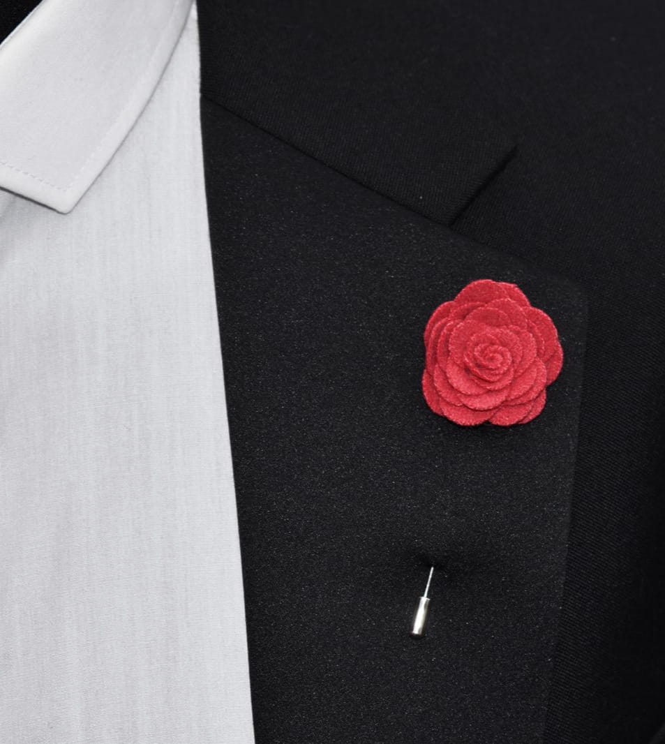 Red flower lapel pin on a black suit jacket