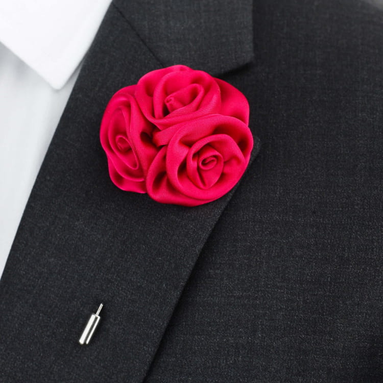 Red rose brooch on a black suit jacket with a white shirt underneath.