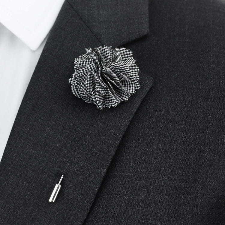 Black suit jacket with a checkered flower lapel pin on a white background
