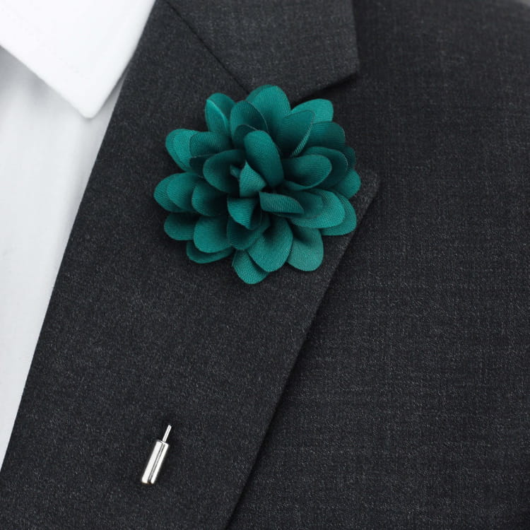 Teal flower lapel pin on a dark gray suit jacket