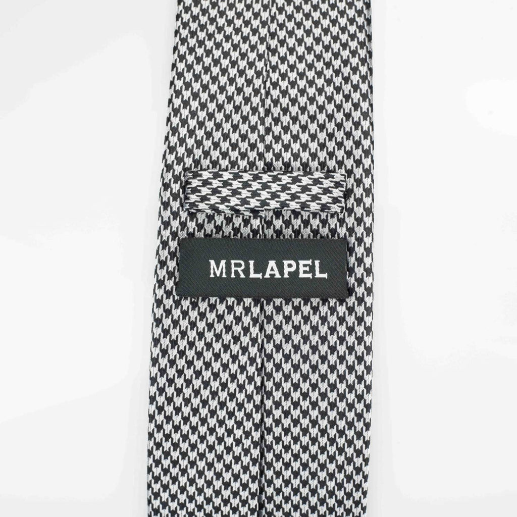 Reverse of grey silk tie photographed against a white backdrop
