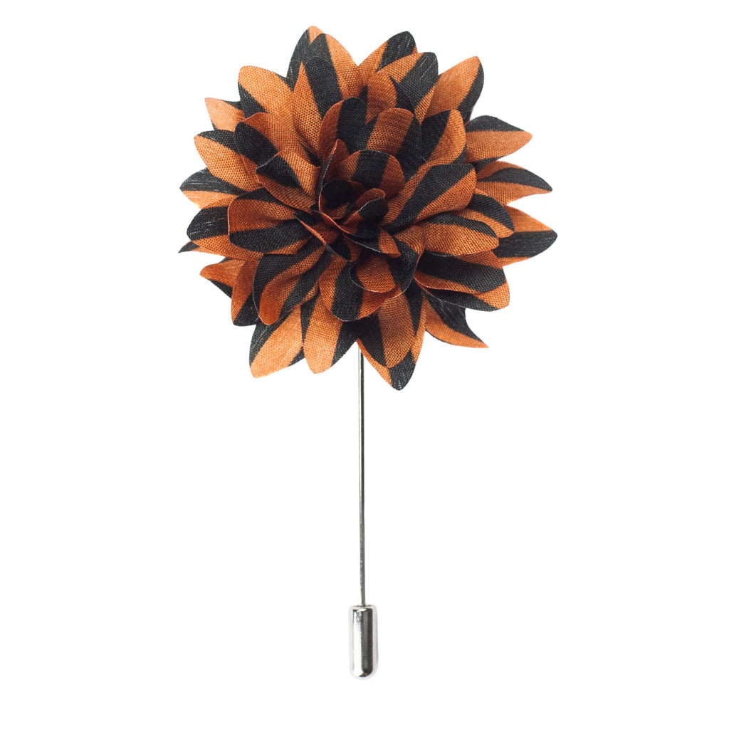 Floral lapel pin with black and orange petals on a white background