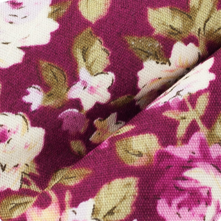 Close-up of floral fabric with pink flowers and green leaves on a purple background