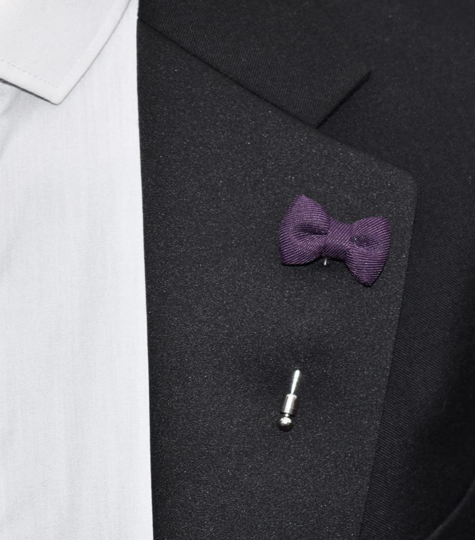 Purple bow tie pin on a black suit jacket