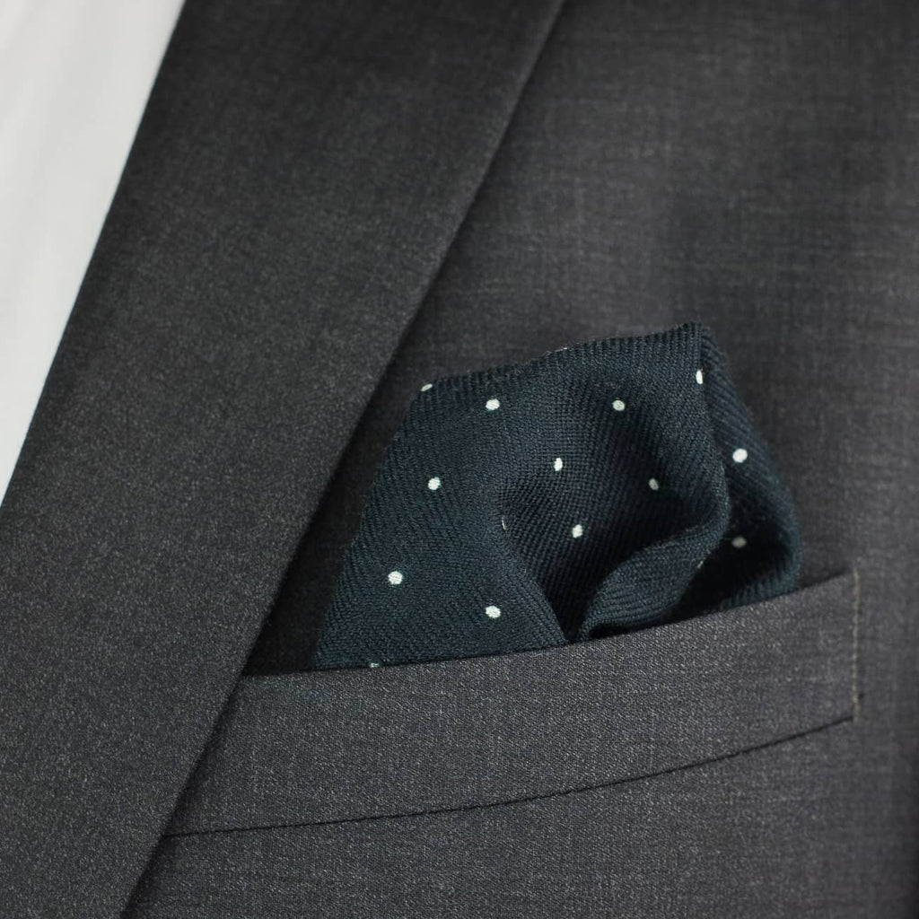 Dark gray suit jacket with a pocket square featuring white polka dots.