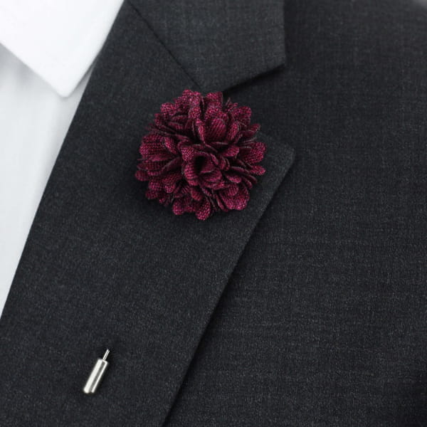 Dark gray suit jacket with a burgundy floral lapel pin on a white background