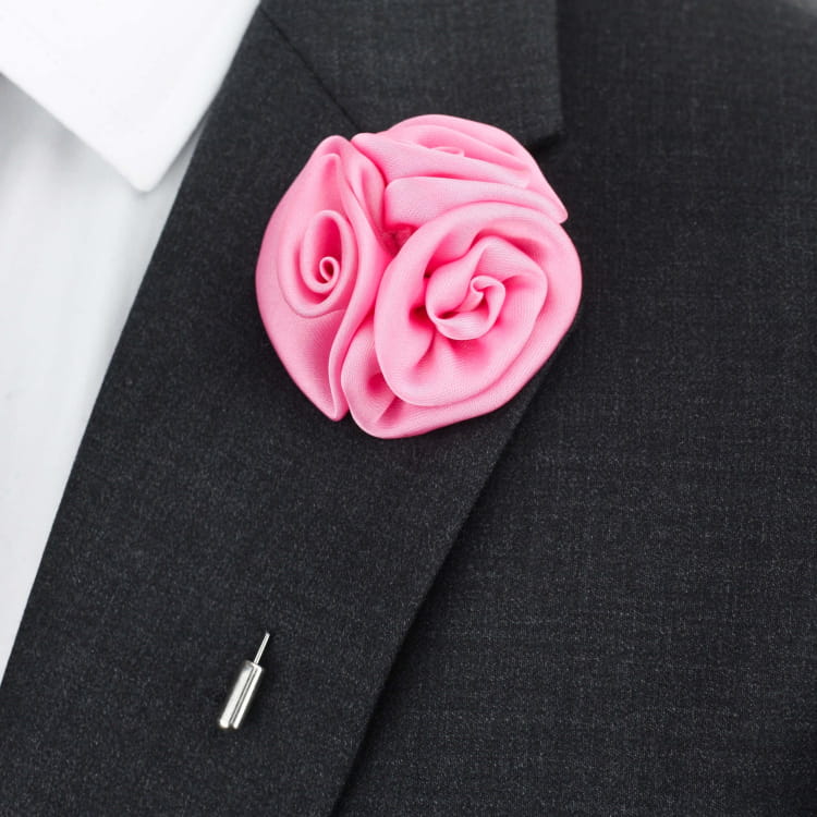 Pink rose-shaped lapel pin on a dark suit jacket