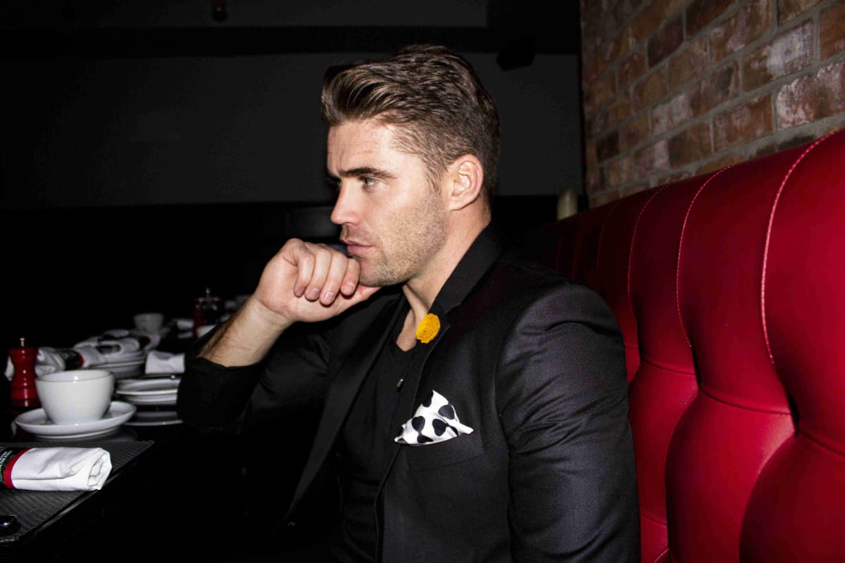 Man in black suit wearing a black and white pocket square with printed bow tie pattern