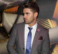 Man in a gray suit with a blue tie standing in front of artistic wall