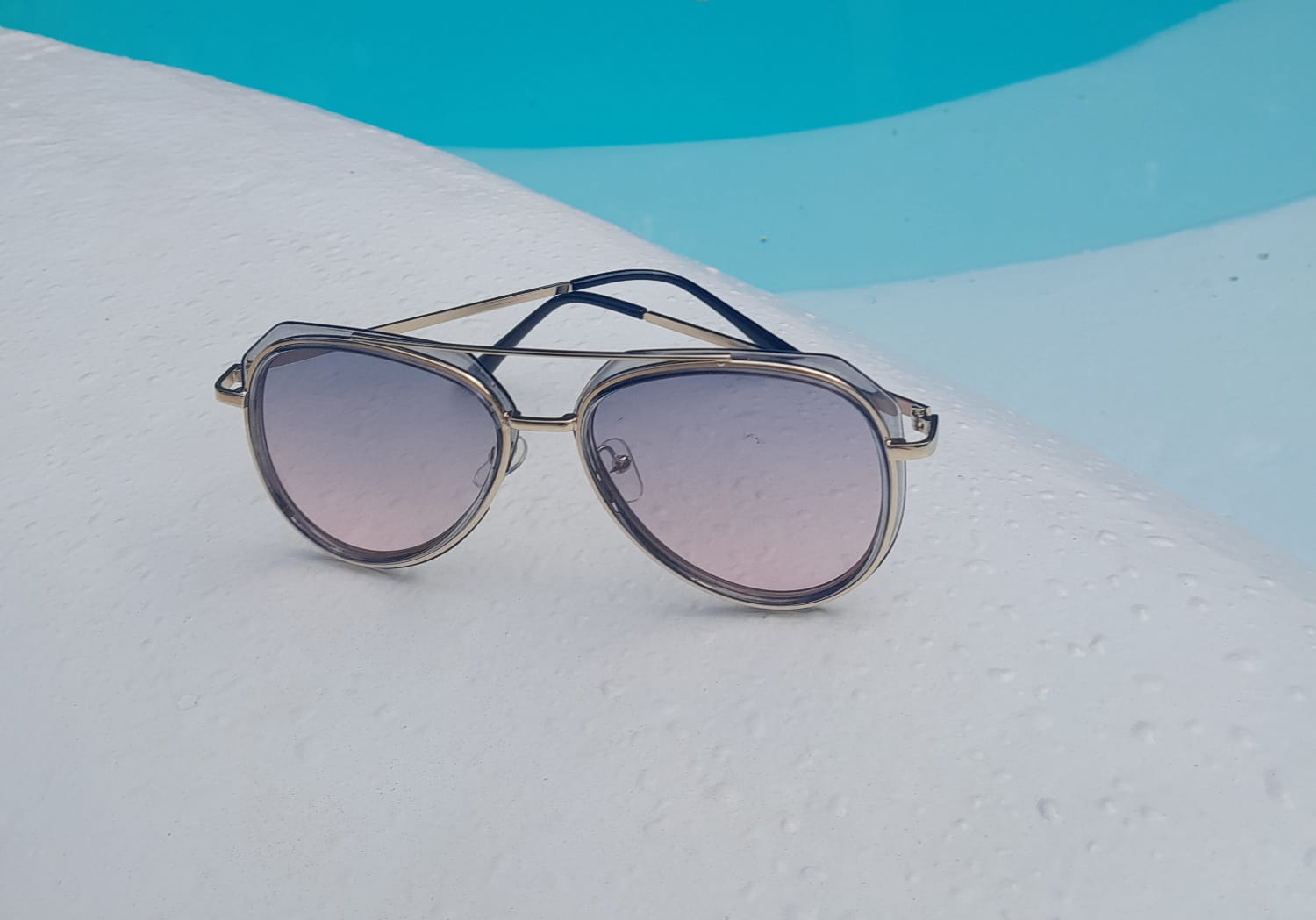 Sunglasses with gradient purple lenses on a white surface with a blue background