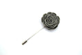 Gray flower-shaped lapel pin on a white background