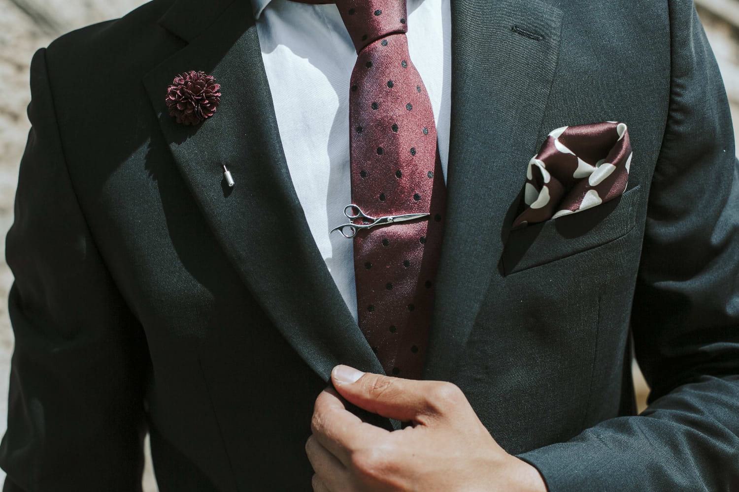 Man wearing a dark suit with a red polka dot tie and matching pocket square.