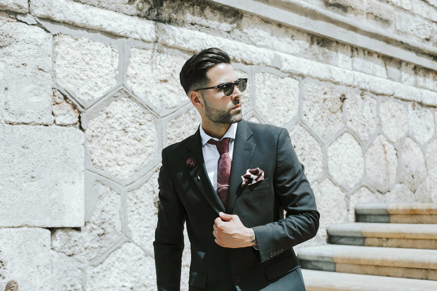 Man in a suit standing against a stone wall