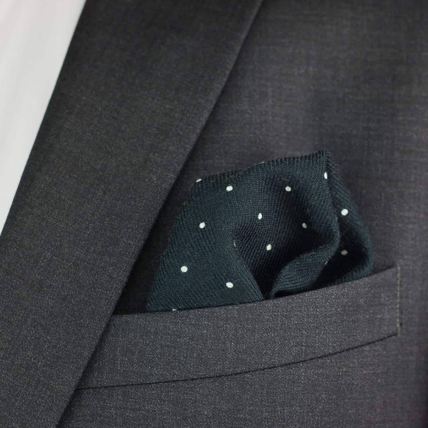 Dark gray suit jacket with a pocket square featuring white polka dots.