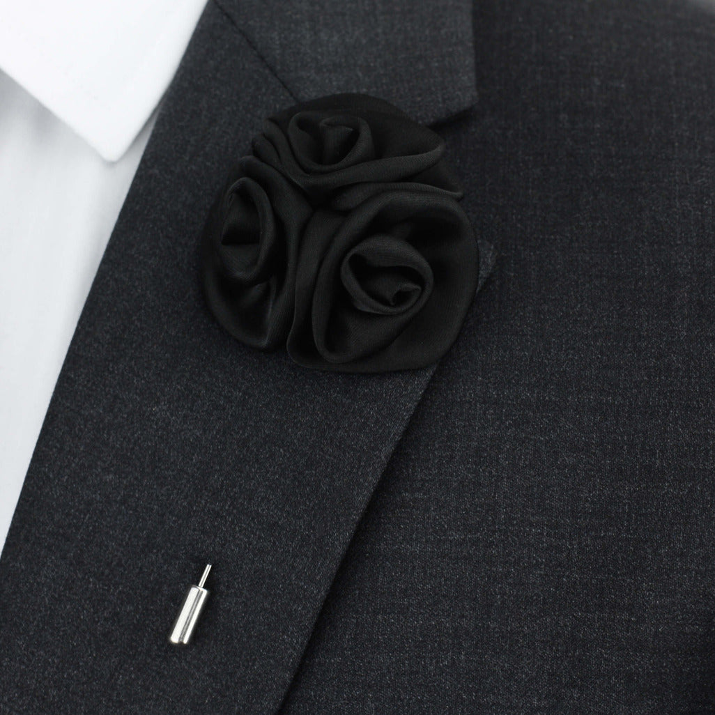 Black rose lapel pin on a dark gray suit jacket