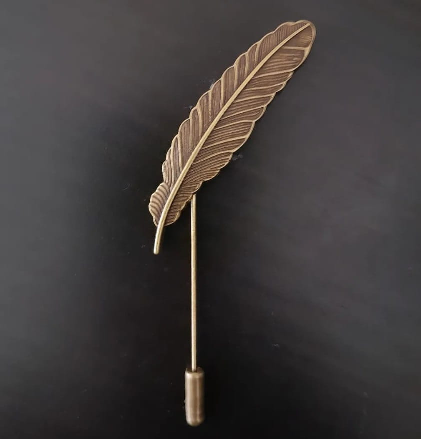 Bronze feather-shaped lapel pin on a black background