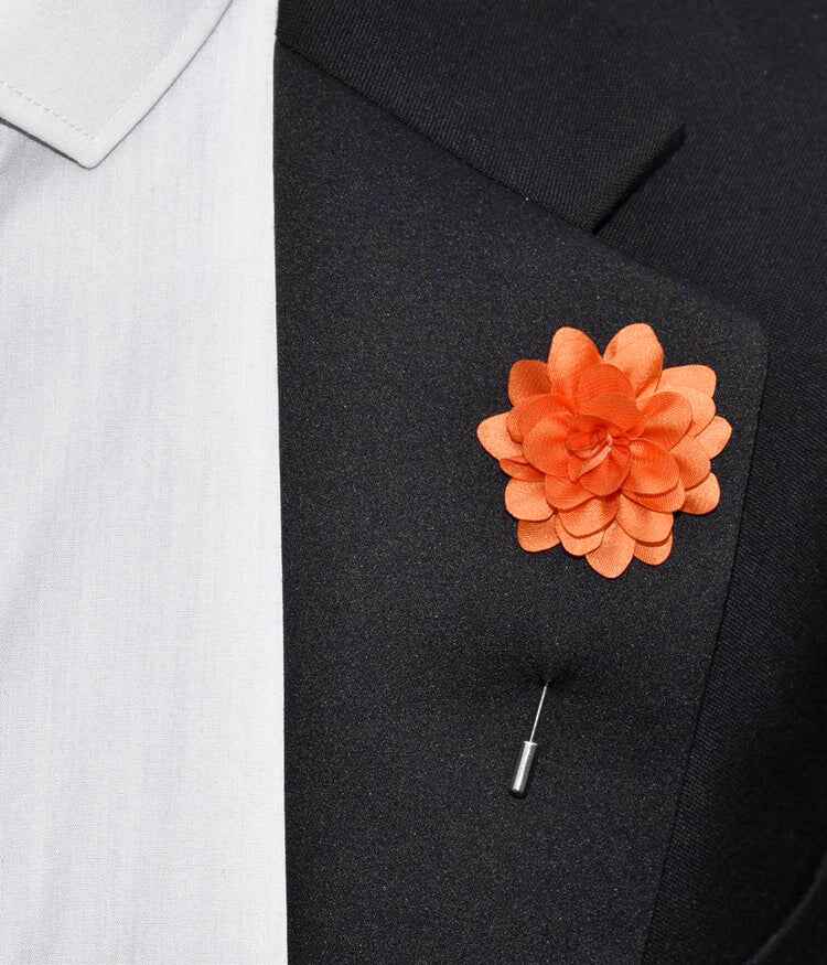 Orange flower lapel pin on a black suit jacket