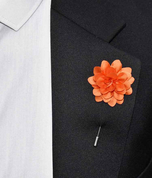 Orange flower lapel pin on a black suit jacket