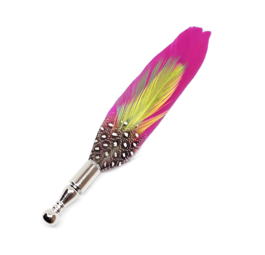 Pink feather lapel pin with second yellow feather on top, photographed against a white backdrop