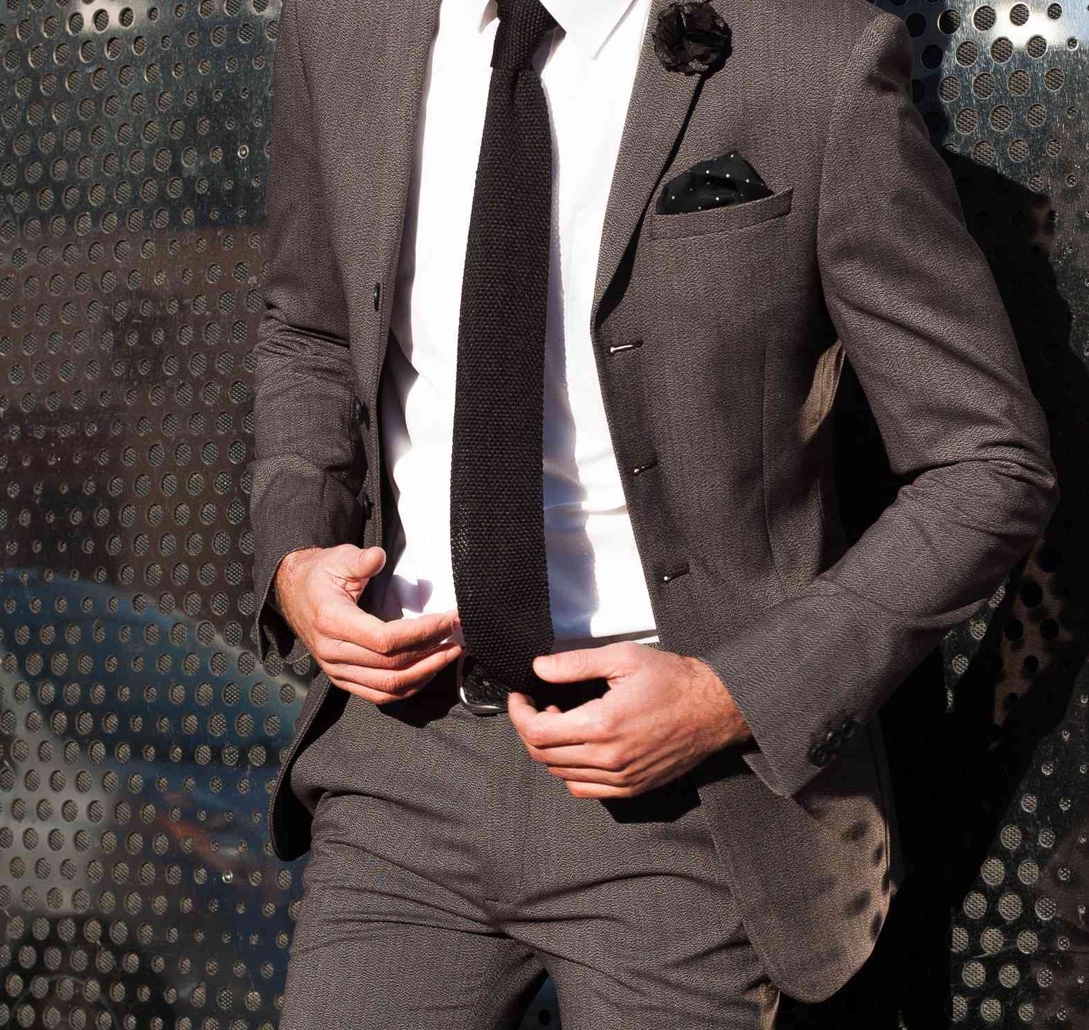 black knitted tie with black pocket square and black lapel pin flower